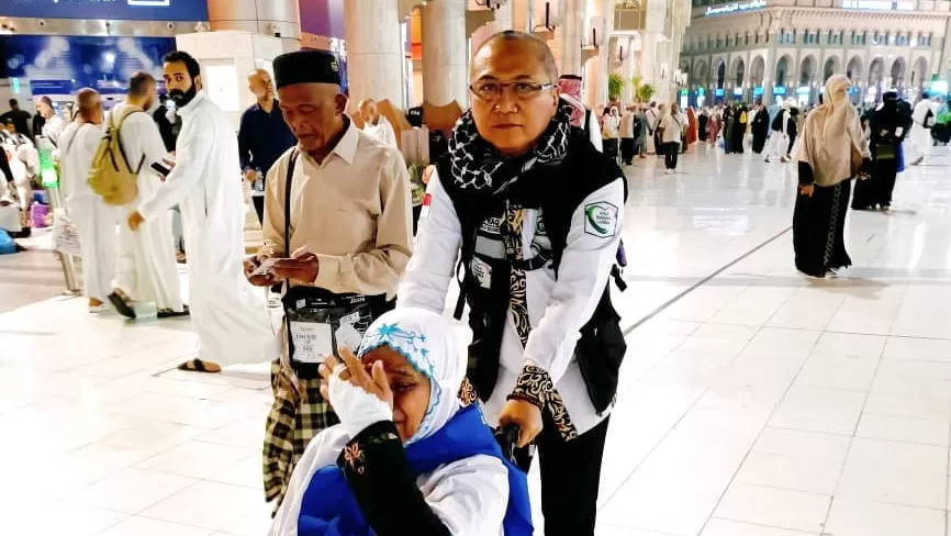 Ishaq Zubaedi Raqib/Penulis (MCH Daker Makkah) mendorong kursi roda jemaah
