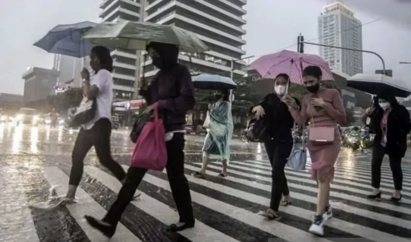 Ilustrasi - Sejumlah karyawati menyeberangi jalan yang tergenang air di depan gedung perkantoran saat hujan ringan.  (ANTARA/Muhammad Adimaja)