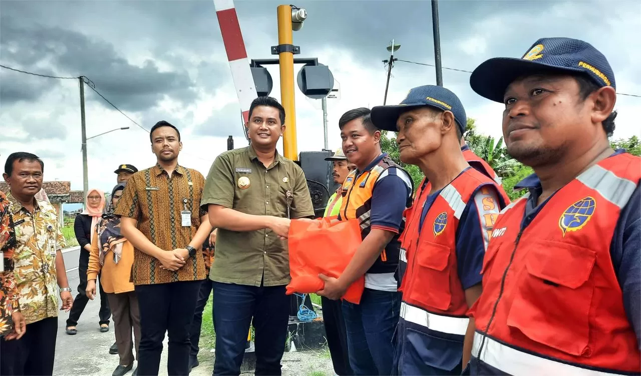   Hamenang dan Benny memberikan bingkisan untuk penjaga palang kereta api di Boto.   (Sri Warsiti)