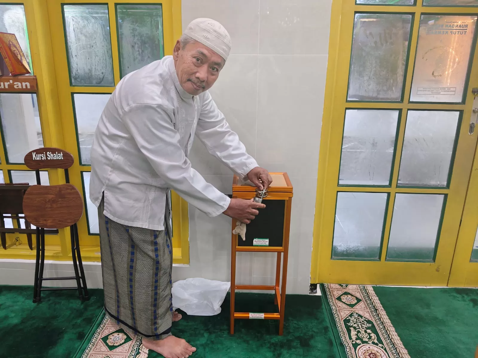 Ketua Takmir Masjid Raudhatul Jannah, KH Mustofa MF menunjukkan kotak infaq yang telah dilengkapi sensor dan alaram di dalamnya yang merupakan karyanya. (Foto Primaswolo S)