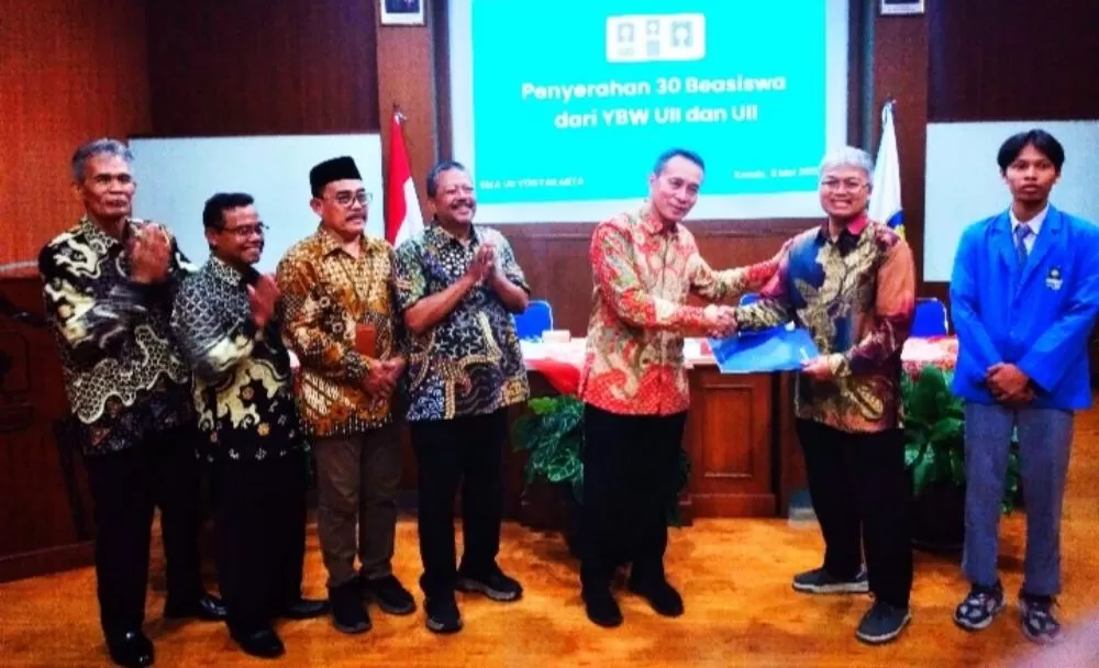  Dr Suparman Marzuki (tengah) secara simbolis menyerahkan beasiswa diterima orangtua dan siswa, didampingi Pengurus YBW UII dan Maman Surakhman MPdI (paling kiri).   (  Foto - Jayadi Kastari)