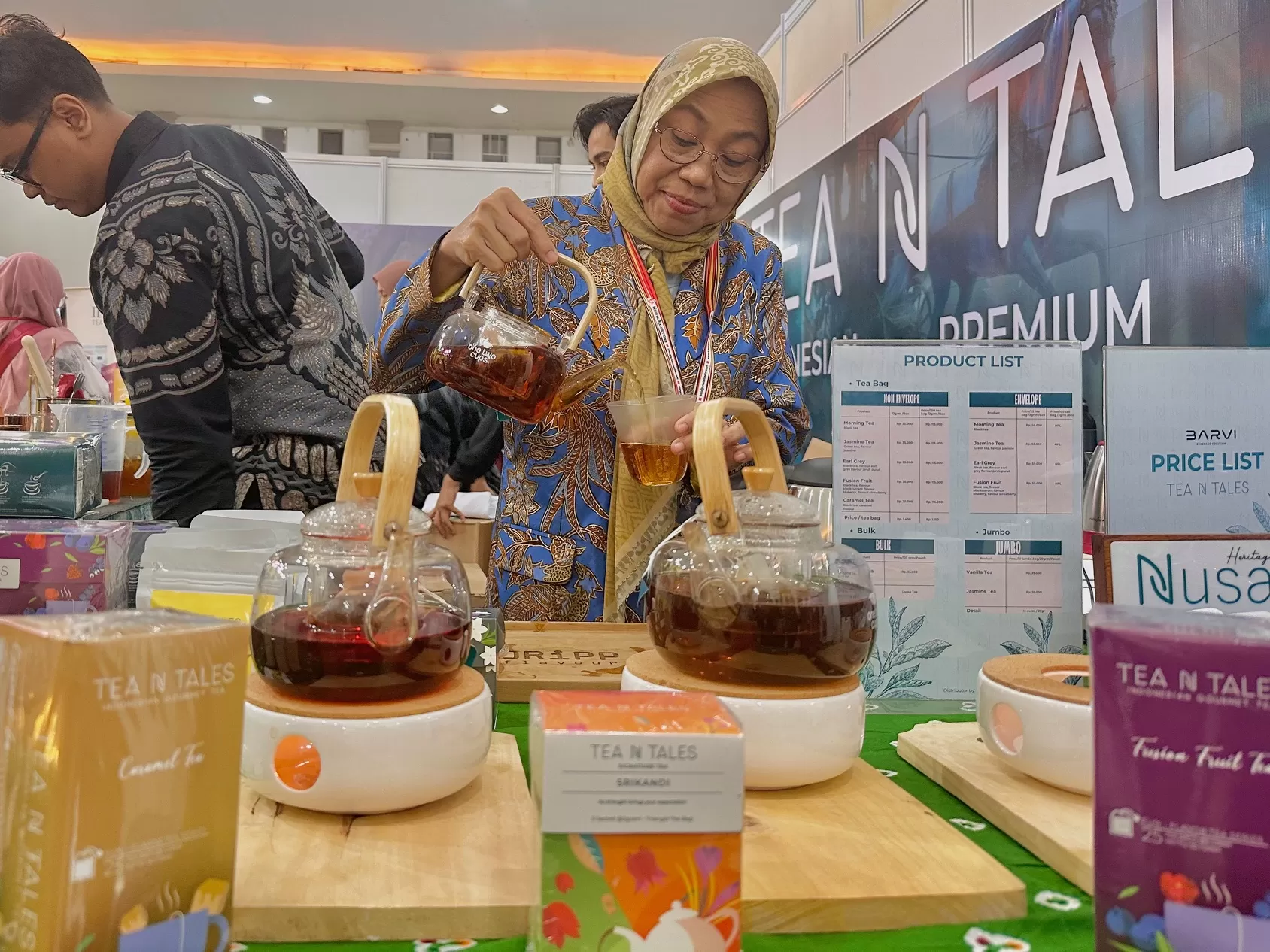   Sri Wahyuni saat menuangkan teh untuk pengunjung (Harminanto)