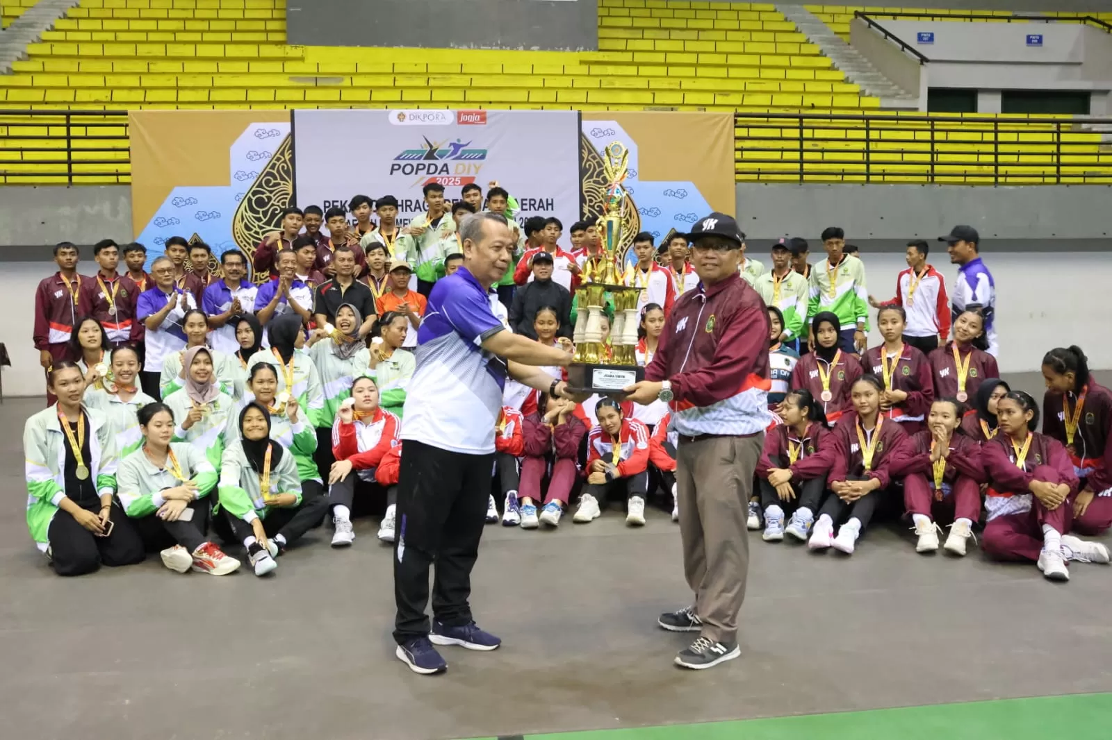  Kepala Disdikpora DIY, Drs Suhirman MPd menyerahkan piala juara umum Popda DIY 2025 kepada Kepala Dinas Dindikpora Kota Yogyakarta, Budi Santosa Asrori SE MM.   (Istimewa)