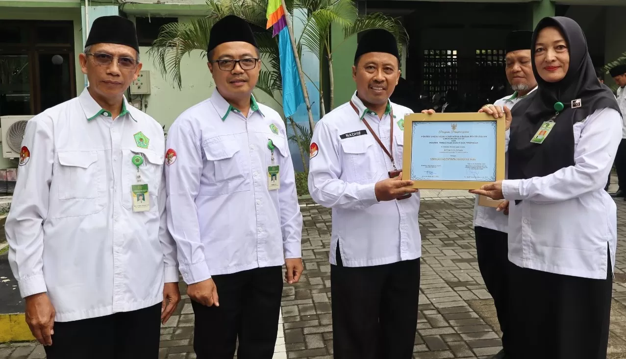 Kepala Kantor Kemenag Sleman, HM Nadhif, menyerahkan piagam Adiwiyata Nasional kepada Kepala MTsN 9 Sleman, Siti 'Jujuk'Juwariyah SPd MSi MSI. (Foto: Istimewa)