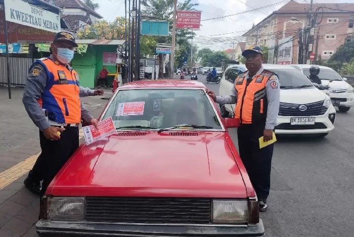Petugas saat menempeli stiker salah satu kendaraan yang parkir liar di Jalan Pulau Nias, Sanglah, Kota Denpasar, Senin (18/9/2023). (rap)