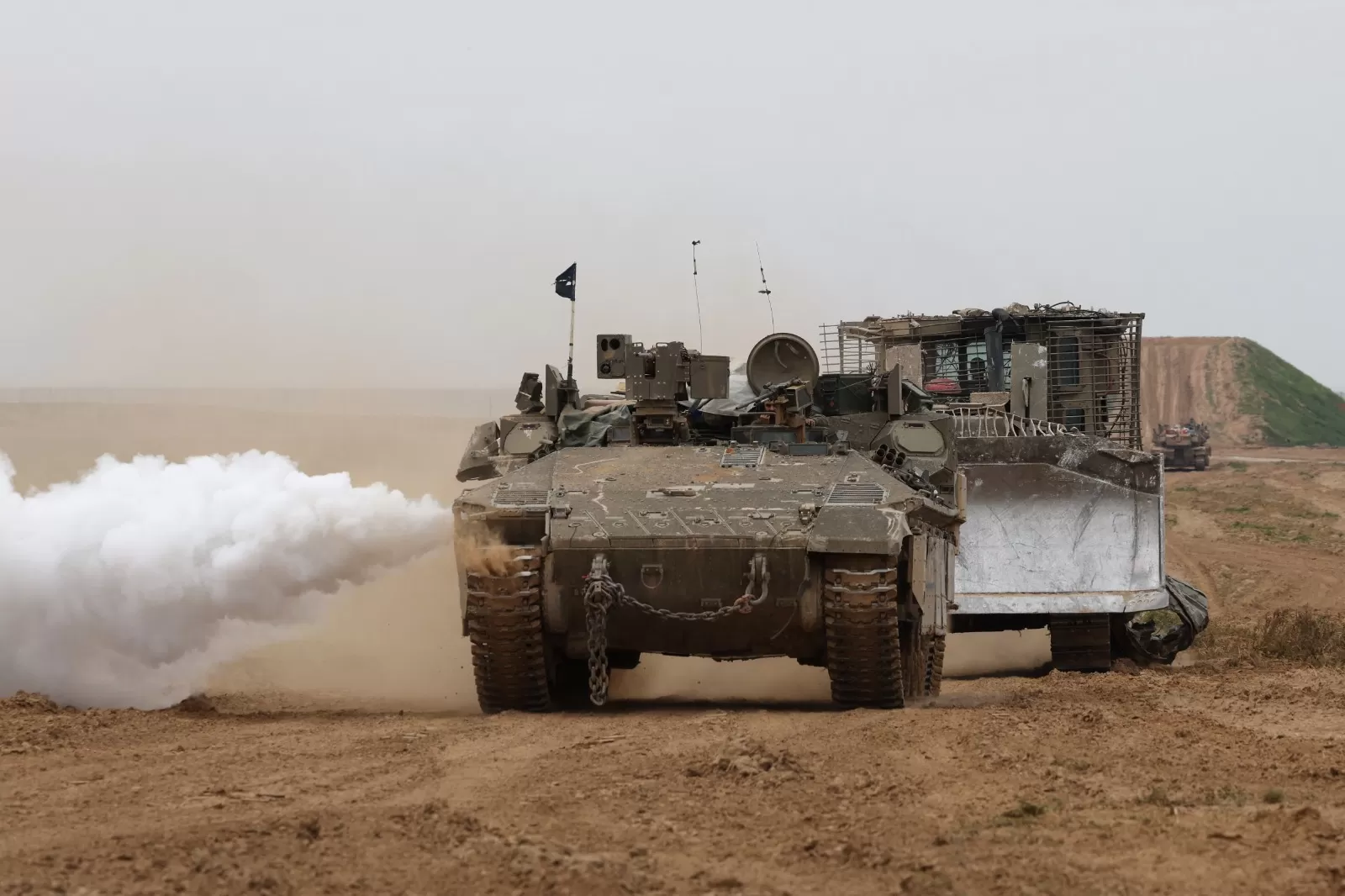 TAK HENTI: Sebuah tank Israel dan kendaraan lapis baja bergerak di sepanjang perbatasan di Jalur Gaza, Jumat (23/2).    (Foto oleh JACK GUEZ / AFP)