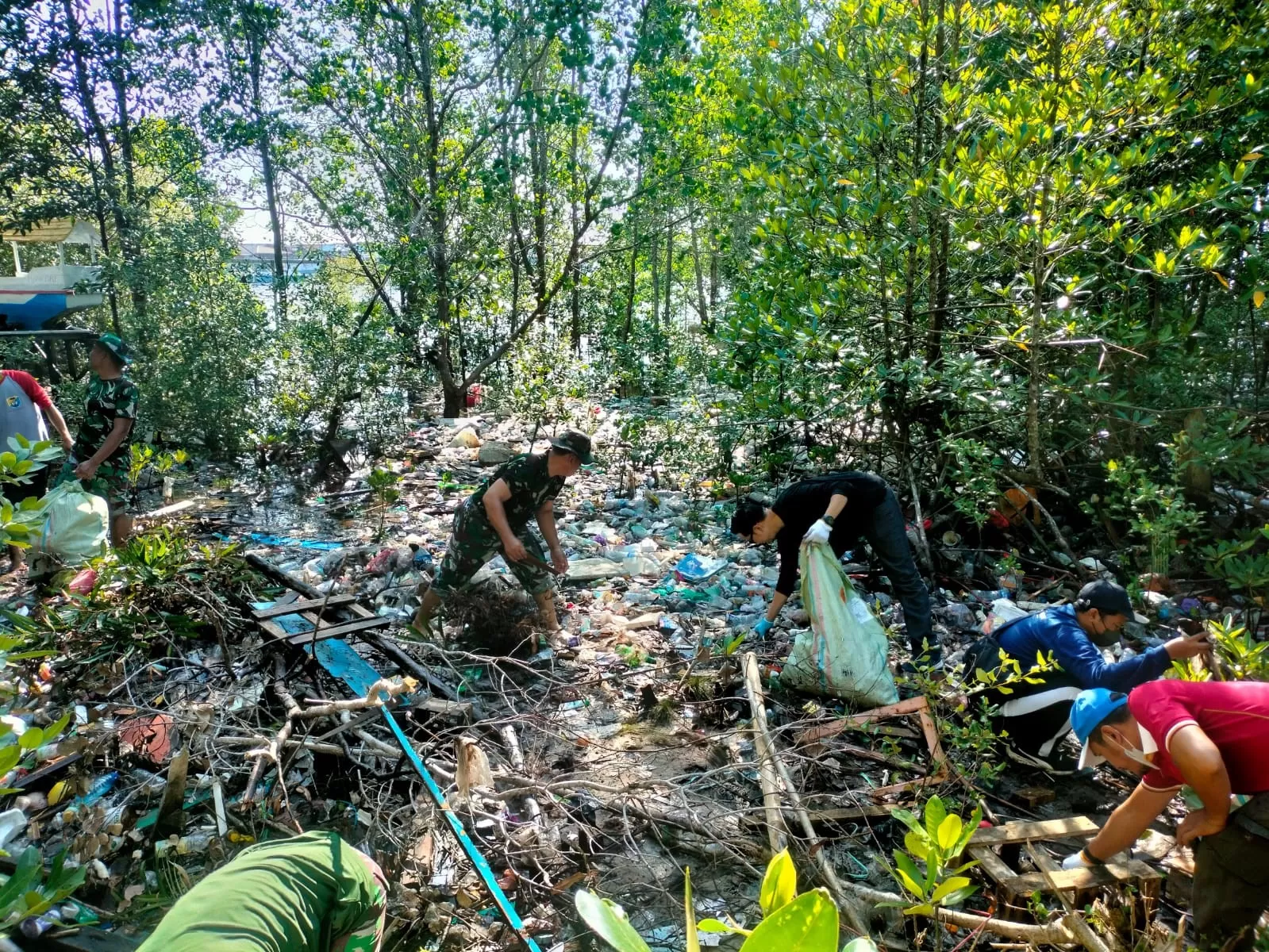 TERBAWA AIR: Tim gabungan dari Dispopar, TNI, dan Polri mengumpulkan tumpukan sampah yang kerap mengotori lokasi wisata Mangrove Berbas Pantai.  