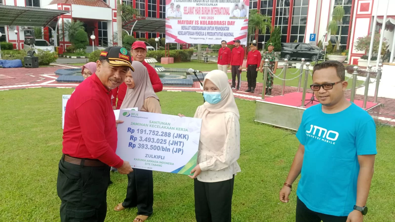 Sekda Kukar Sunggono menyerahkan santunan jaminan kecelakaan kerja pada apel Hari Buruh Internasional 2025 (Elmo/Prokal.co)