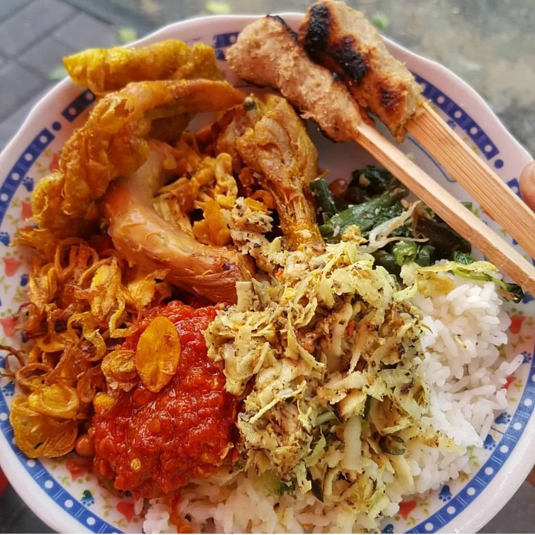 Nasi Campur Men Weti menawarkan berbagai lauk seperti ayam betutu, sate lilit, dan lawar yang berpadu dalam satu porsi nasi. (Instagram / @infodenpasar)