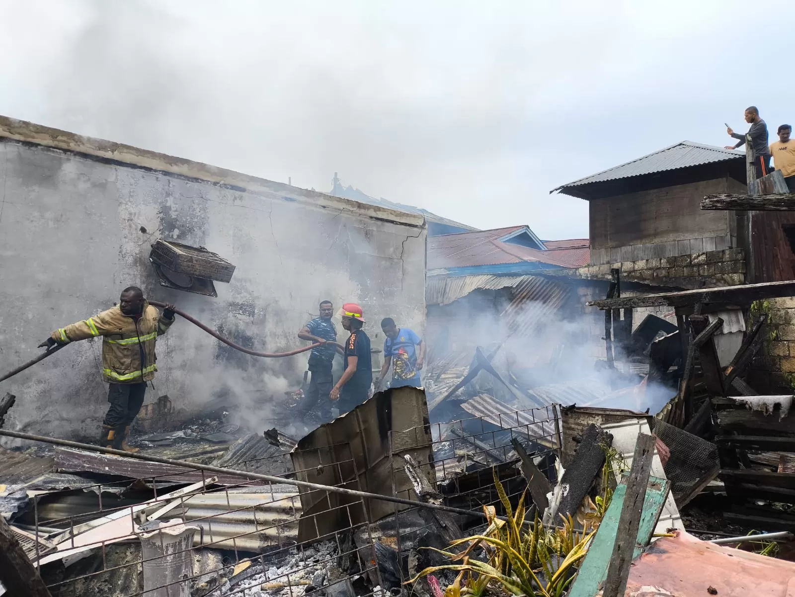 Petugas pemadam kebakaran saat berupaya memadamkan api di lokasi kebakaran yang berada di belakang Kampus Umel Mandiri, Kotaraja, Jumat (14/3/2025).
