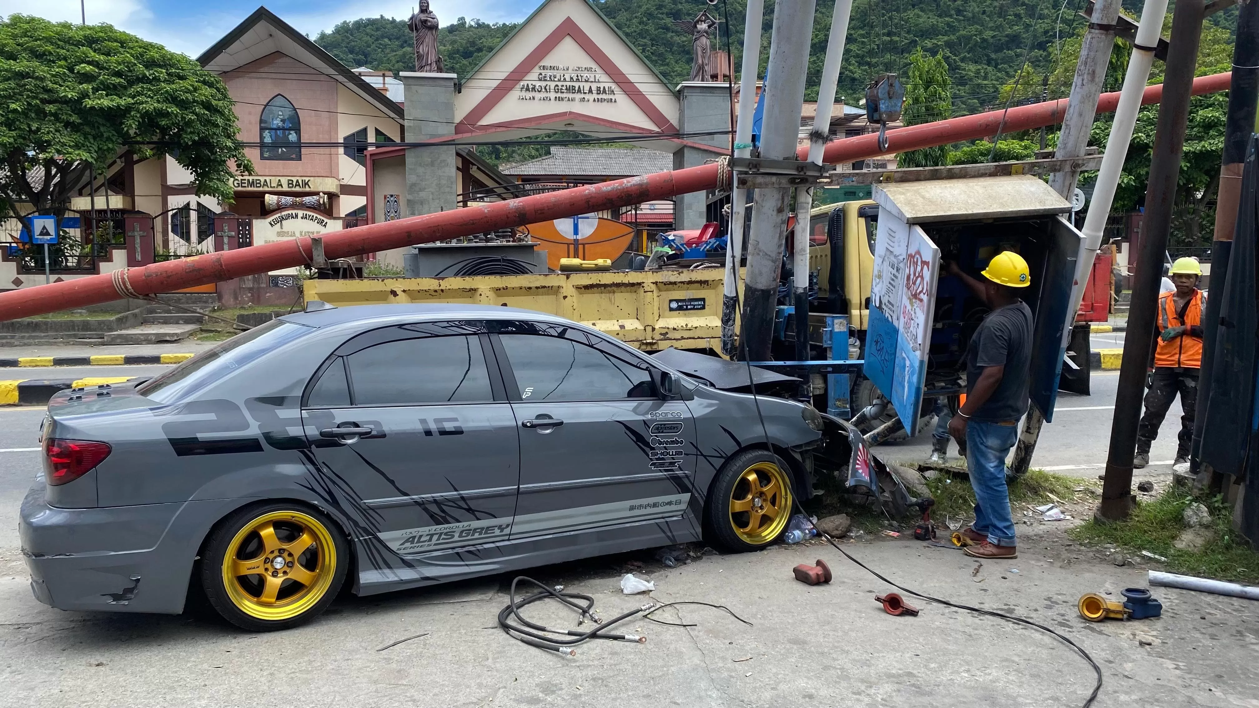 Kondisi Mobil tanpak rusak parah bagian depan dan pihak PLN dari ULP Abepura sementara memperbaiki kerusakan aliran listrik, Sabtu (15/3/2025). Jimi/Cepos