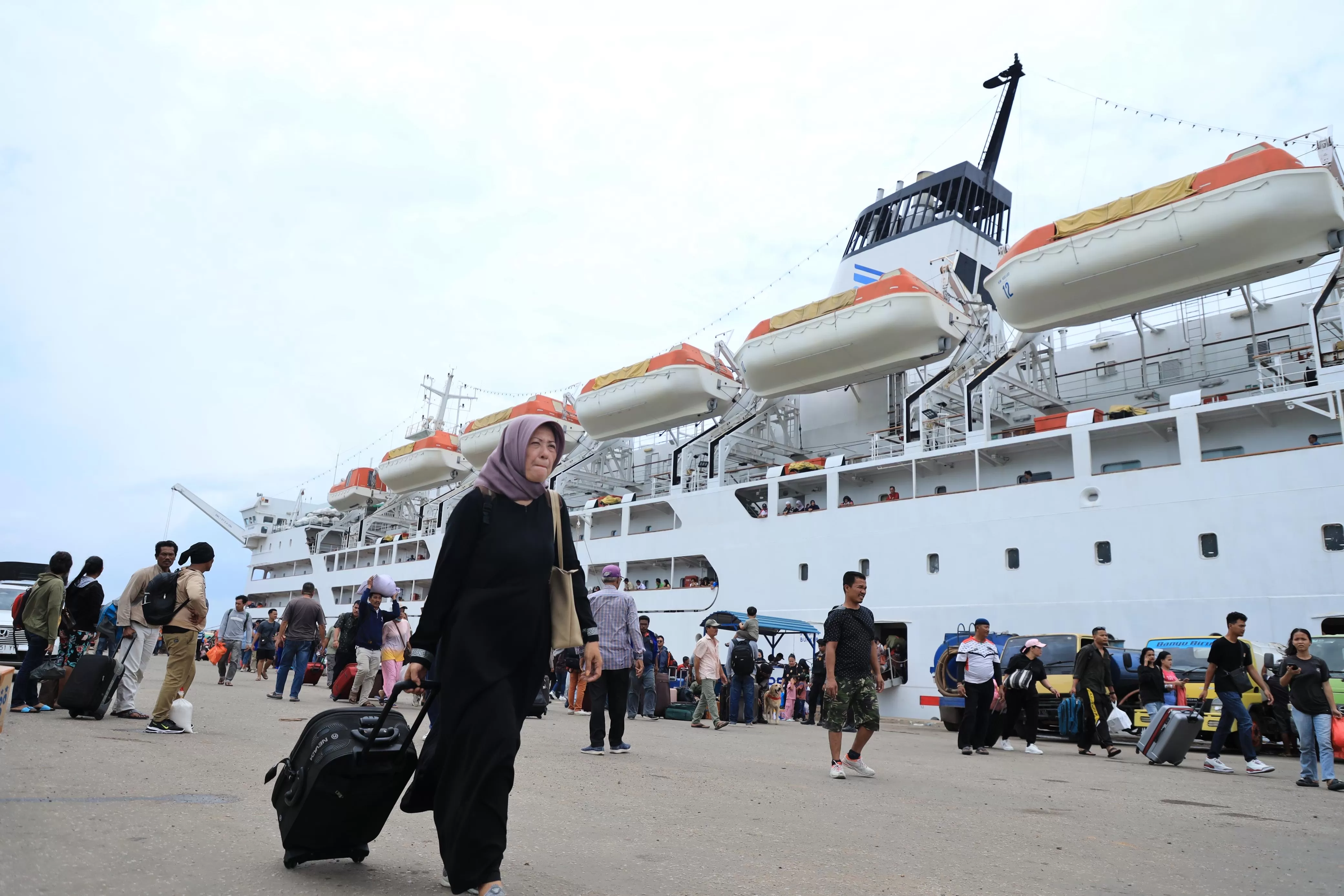 Seorang penumpang sedang berjalan di dermaga sambil menarik koper miliknya dengan penampakan Armada Pelni di belakangnya. (PELNI CAB. MIMIKA).  