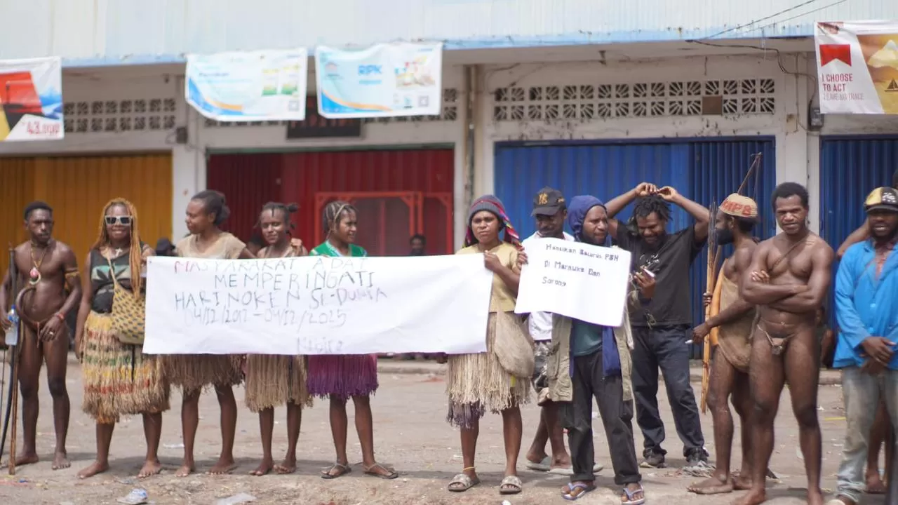 Sejumlah pemuda-pemudi Papua Tengah dengan mengenakan busana daerah saat membentangkan spanduk protes pengrusakan lingkungan di area Pasar Karang Nabire, Kamis (4/12/2025).