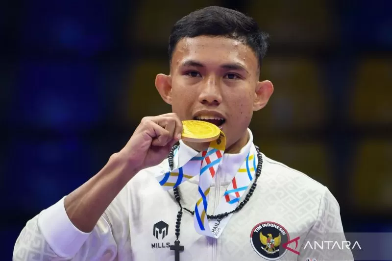 Petarung Indonesia Riyan Lumbanbatu menggigit medali emasnya usai mengalahkan petarung Thailand Jakkrit Kongtook dalam babak final nomor K-1 60 kilogram putra cabang Kickboxing SEA Games 2025 Thailand