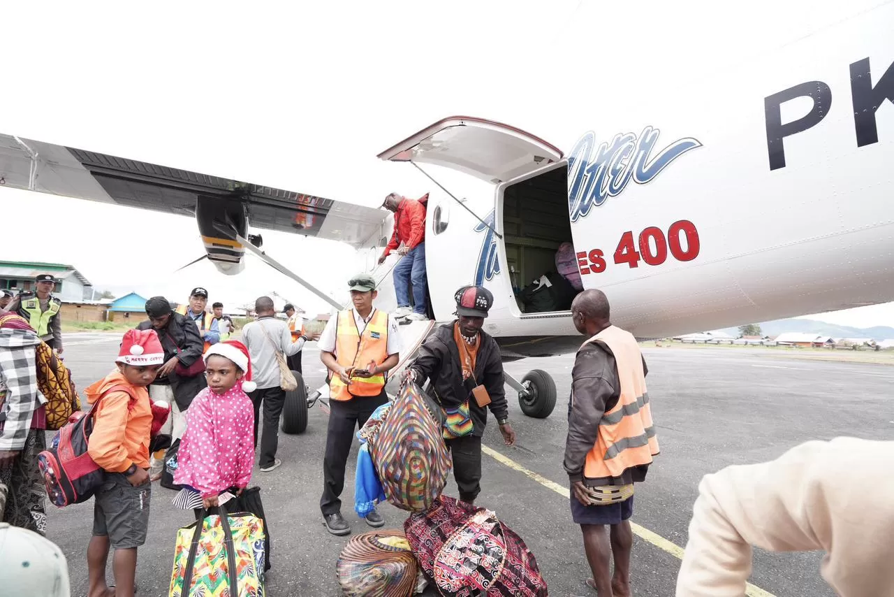 Karyawan dan keluarga tiba di Bandar Udara Enarotali di Kabupaten Paniai sedang mengeluarkan bagasi dari Pesawat Twin Otter. (Foto: Dokumen PTFI).