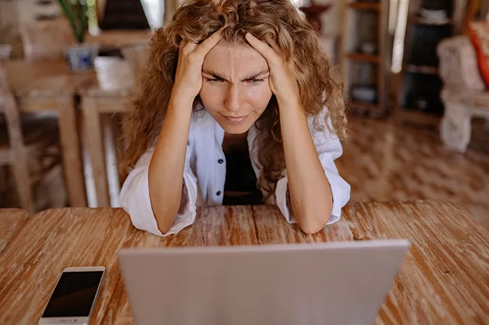 Seorang wanita pusing memegang kepala didepan laptop (Photo by Yan Krukau)