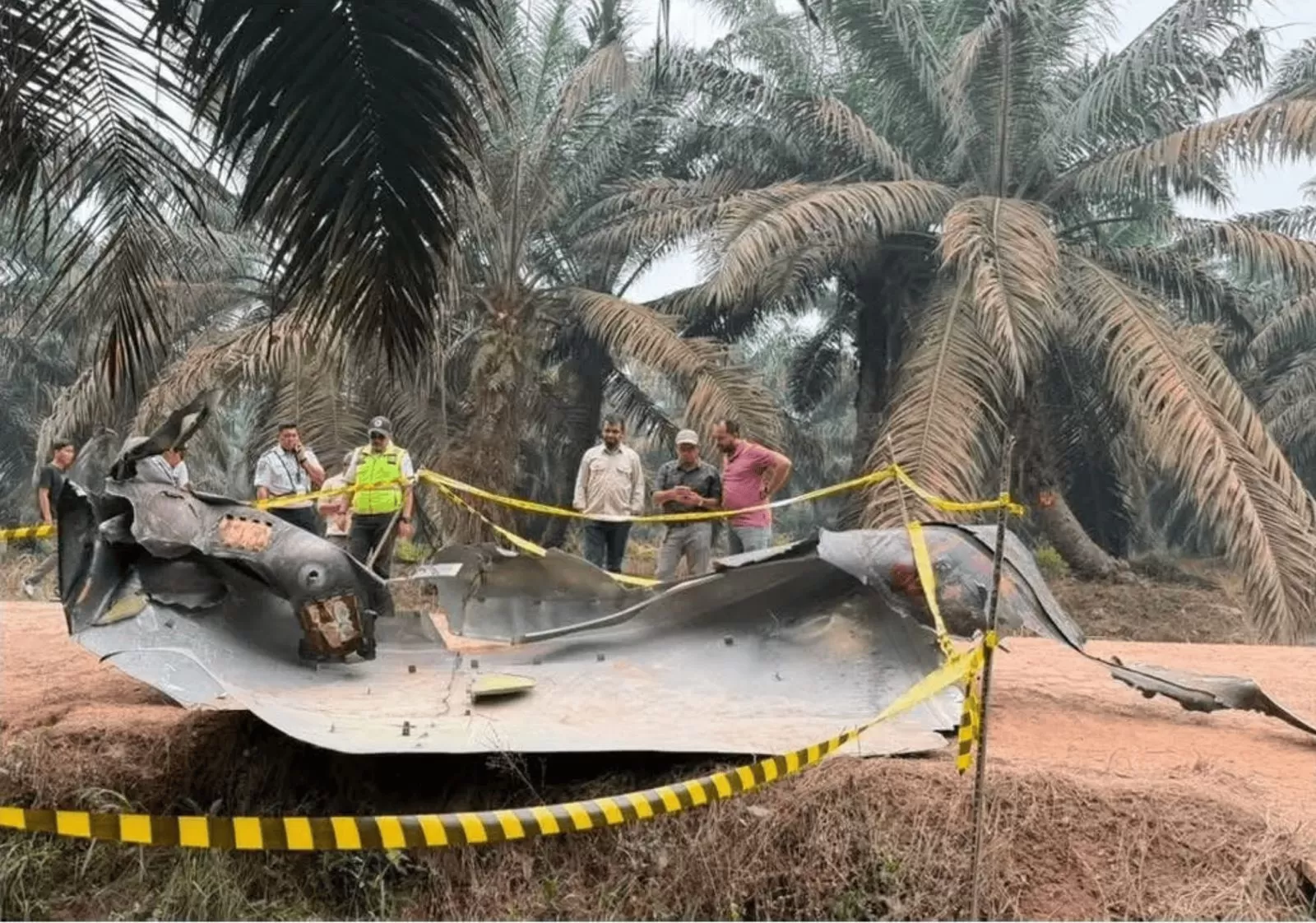 Serpihan yang diduga bagian dari roket China ditemukan di perkebunan sawit Sampit, Kalimantan Tengah. Petugas memasang garis polisi di sekitar lokasi. (Sumber: Threads/@uthmandaud)