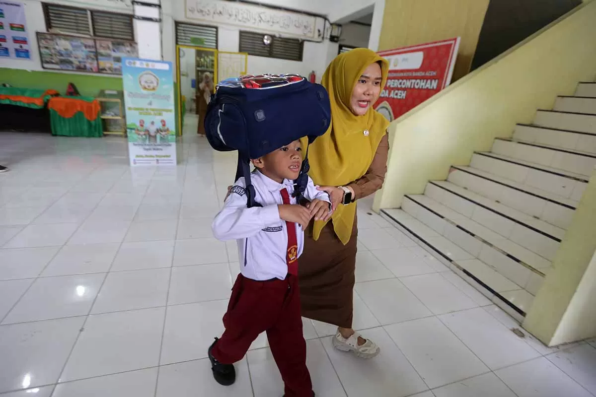 Seorang guru bersama siswa berjalan menuju titik kumpul saat berlangsung simulasi gempa dan tsunami di SDN 67 percontohan Banda Aceh, Senin (5/10/2026). Aentenews Foto/Ampelsa.