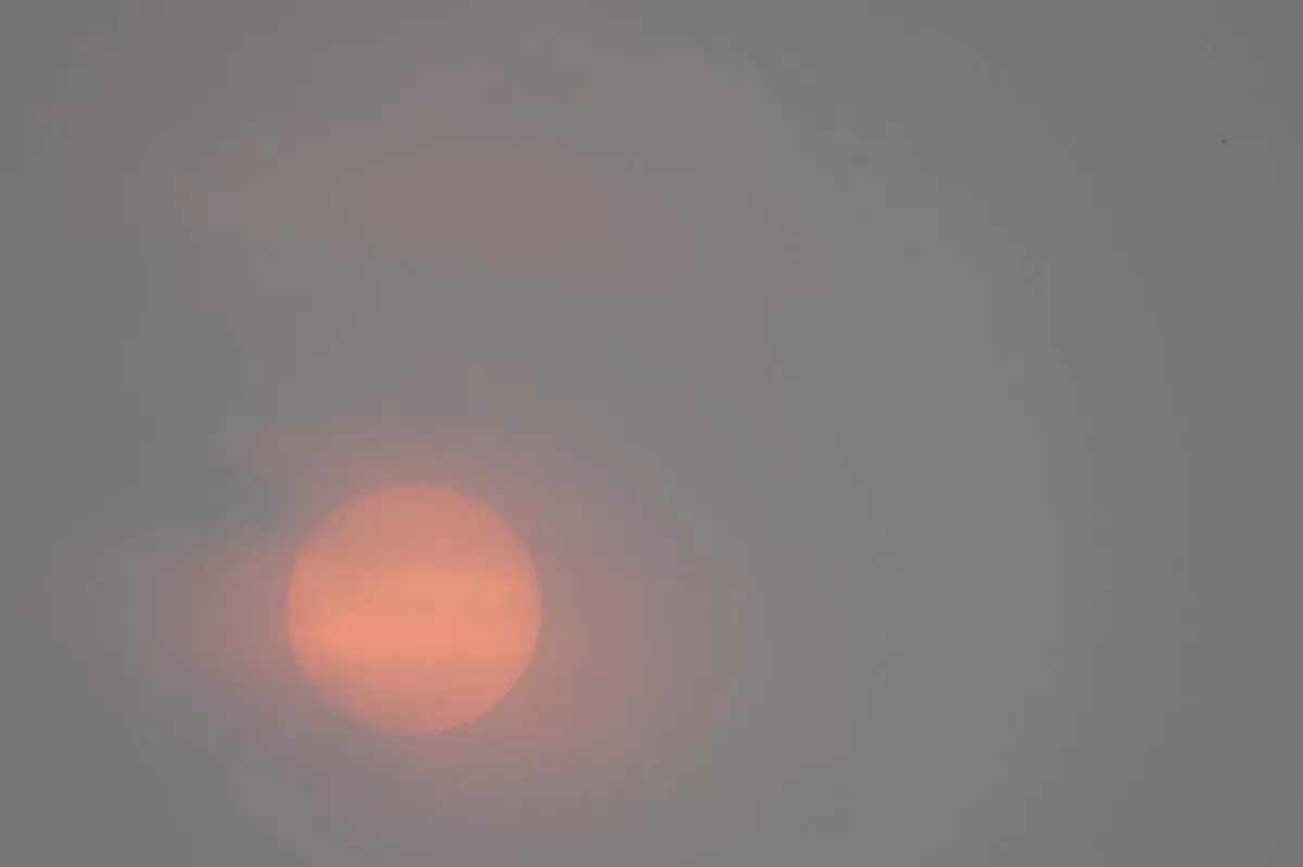 Fenomena Matahari merah saat wilayah udara terpapar asap Kebakaran Hutan dan Lahan (Karhutal) menarik perhatian banyak warga pada waktu menjelang sore di Banda Aceh., Jumat (16/10/2026). Aentenews Foto/Ampelsa