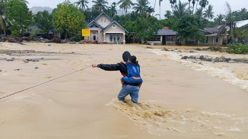 Warga terdampak banjir di Kota Padang , Sabtu (10/10/2026) melewati arus sungai yang debitnya meningkat akibat hujan deras untuk upaya evakuasi diri. (Foto: Faktajurnalis.id)