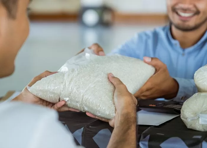 Ilustrasi orang muslim sedang menyerahkan beras untuk zakat fitrah ((Foto: GENMUSLIM.id/dok: Iim Maya Sofa/ Canva))