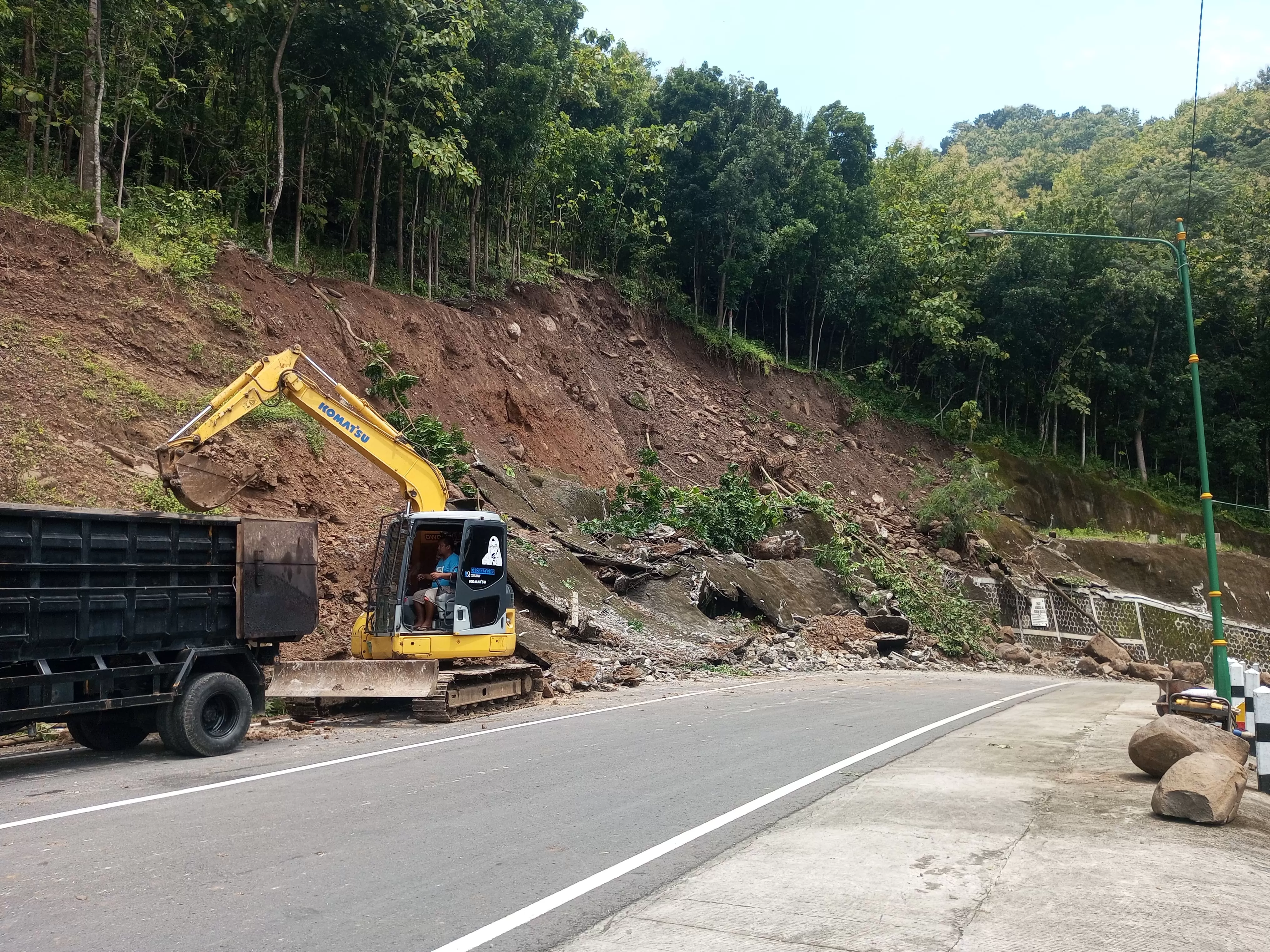 Pembersihan material longsoran di jalur tanjakan Clongop menggunakan alat berat.