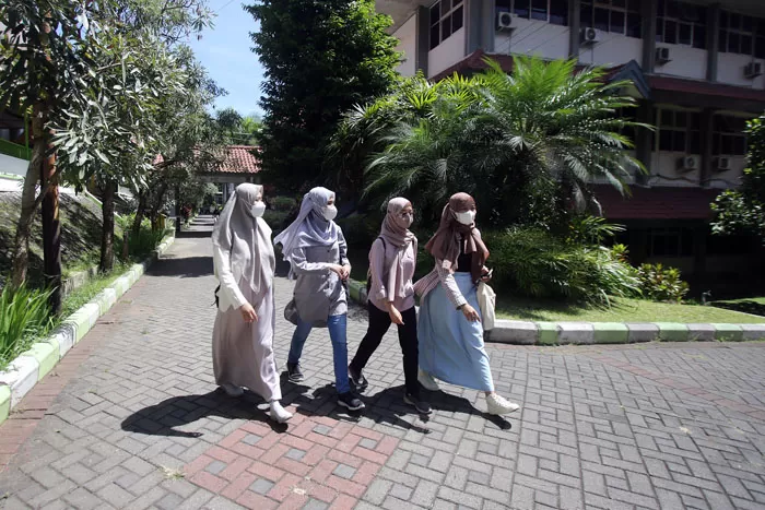 Mahasiswi Universitas Negeri Malang berjalan di area kampus (Suharto/Radar Malang)