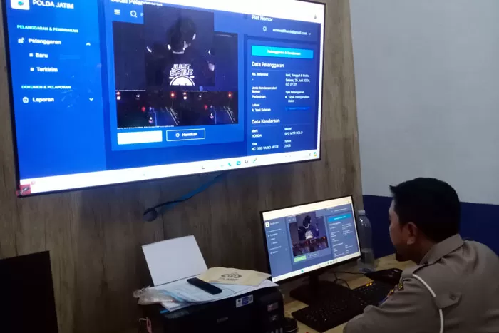 Petugas back office ETLE statis meneliti ulang gambar pengendara motor yang terekam kamera tidak mengenakan helm di Jalan Ahmad Yani. (NAHDIATUL AFFANDIAH/RADAR MALANG)