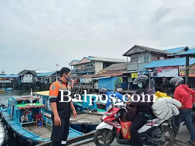 PANTAU PENGUNJUNG : Salah satu petugas Dinas Perhubungan memberikan arahan ke masyarakat tentang protokol kesehatan di Pelabuhan Kelotok Kampung Baru Tengah.