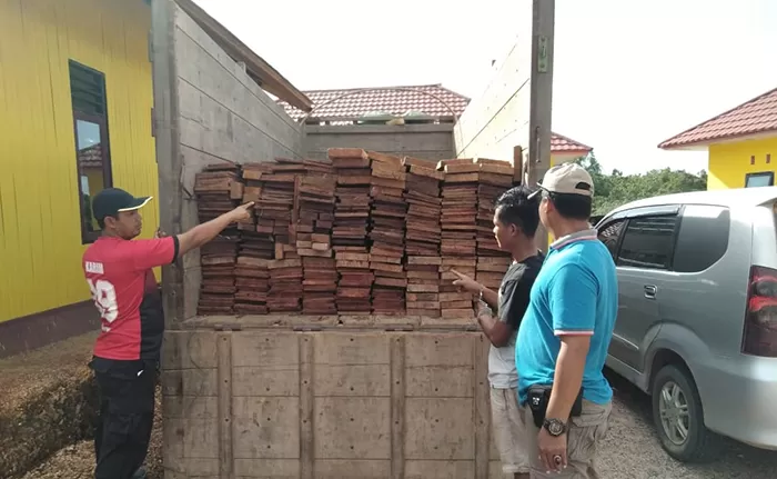 DIAMANKAN: Deni bersama truk dan barang bukti berupa kayu ilegal yang kini diamankan di Mapolsek Kelay, kemarin (5/2).