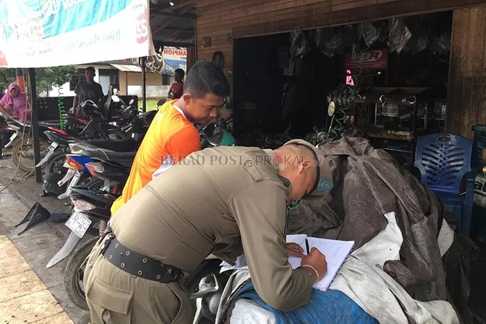 DIBERI PERINGATAN: Petugas Satpol PP Berau saat memberi peringatan terhadap pemilik bengkel di Jalan Gatot Subroto, Tanjung Redeb, kemarin (12/2).