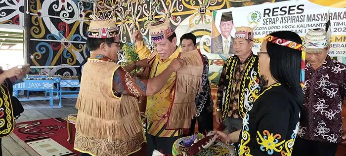 GELAR ADAT: Ketua DPRD Kaltim Makmur HAPK yang diberi gelar Pemimpin Besar, dibantu untuk mengenakan pakaian adat serta aksesori Dayak, di sela-sela pelaksanaan reses di Desa Makmur Jaya, Kecamatan Kongbeng, Kutai Timur, kemarin (13/2).