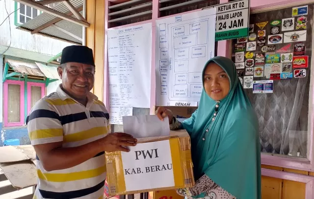 PWI BERBAGI: Ketua PWI Berau Abdul Azis Sakti, menyerahkan bantuan secara simbolis kepada Putri, perwakilan ketua RT 02 Kelurahan Bugis, Sabtu (14/3).