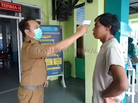 TES SUHU TUBUH: Petugas Puskesmas Tanjung Redeb memeriksa suhu tubuh salah seorang pengunjung puskesmas.