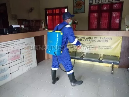 CEGAH PENYEBARAN CORONA: Petugas saat menyemprotkan disinfektan di kantor Kelurahan Karang Ambun kemarin.