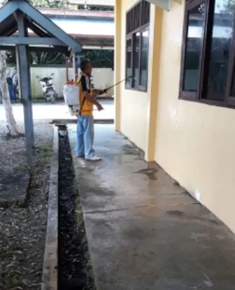 STERILISASI: Personel Kelurahan Gunung Tabur melakukan penyemprotan cairan disinfektan di bagian lura kantor, sebelum membuka pelayanan bagi masyarakat Senin (8/6) nanti.