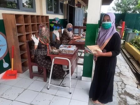 DIKELUHKAN: Salah seorang wali murid hendak mengumpulkan tugas kepada guru yang menunggu di lorong SD 007 Tanjung Redeb.