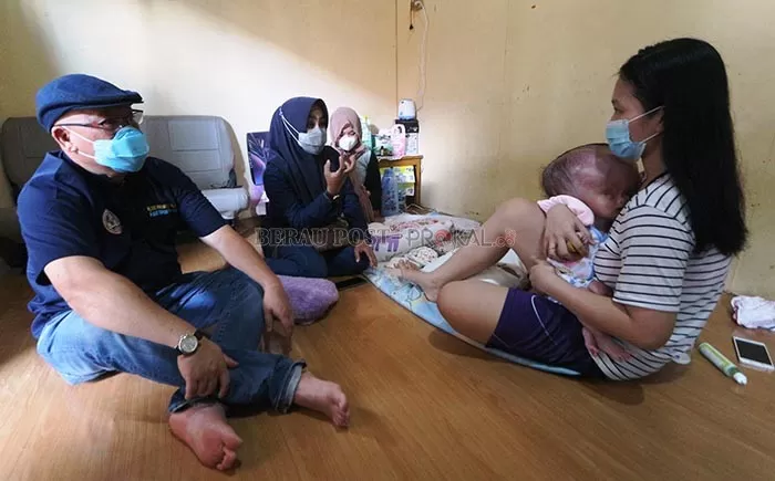 PRIHATIN: Jekonia Kalina Kilahong, bayi yang memilki kelainan pada kepala digendong oleh orangtuanya.