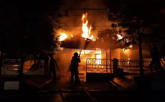 KEBAKARAN: Petugas pemadaman kebakaran berusaha memadamkan kobaran api yang melahap satu rumah dinas, malam tadi (22/12).