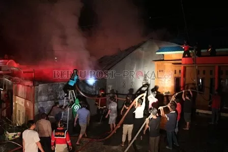 PENDINGINAN: Tim pemadam kebakaran dari BPBD Berau, bersama sejumlah warga berupaya memadamkan kobaran api yang menghanguskan satu unit rumah  di Komplek Asri Mandiri, Jalan Murjani II, Tanjung Redeb, Sabtu (12/6).