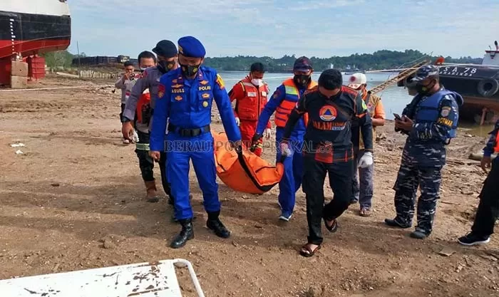 EVAKUASI: Petugas dibantu warga mengevakuasi jenazah ABK yang terjatuh dari atas kapal, Minggu (18/7).