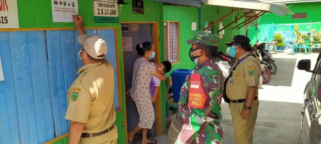 TEMPELI STIKER: Petugas Satgas Kelurahan Bugis saat menempeli stiker di kediaman pasien isolasi mandiri di wilayahnya.