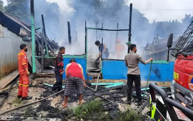 PENDINGINAN: Petugas pemadam kebakaran dibantu sejumlah warga melakukan pendinginan rumah warga yang hangus terbakar.
