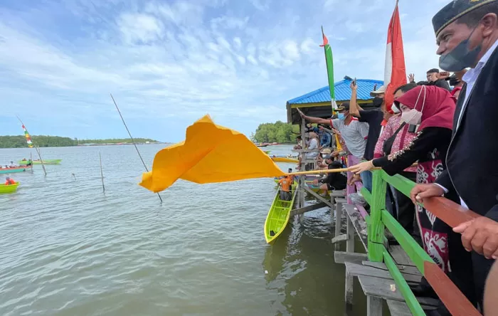 PELEPASAN LOMBA: Bupati Berau Sri Juniarsih Mas mengibarkan bendera kuning, tanda dilepasnya lomba perahu dompeng dan ketinting di Kampung Buyung-Buyung, kemarin (14/10).