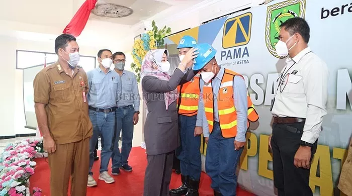 SIMBOLIS: Bupati Berau Sri Juniarsih, memasangkan helm kepada peserta yang akan mengikuti wisuda operator dan mekanik yang dilaksanakan PT Pamapersada Nusantara di kantor Disnakertrans Berau kemarin (9/8).
