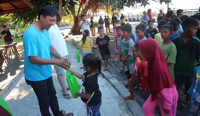 BAGIKAN PAKET: Ketua PWI Berau Yudhi Perdana, didampingi pembina Berau Journalist Divers (Berjudi) Agus Tantomo saat memberikan paket peralatan sekolah kepada 100 anak di Pulau Maratua, kemarin.