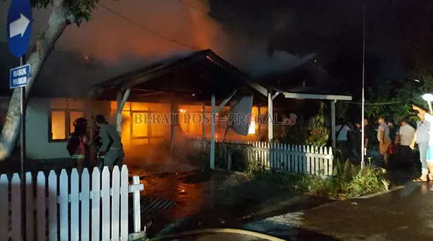 BERJIBAKU: Petugas Damkar bersama personel Polres Berau, berupaya memadamkan api yang melahap satu bangunan dua pintu di kompleks asrama polisi tadi malam.