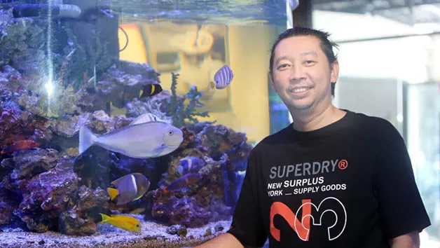 BERBAGI TIPS: Steven Pontoh berpose bersama koleksi Botana Naso di akuarium miliknya.