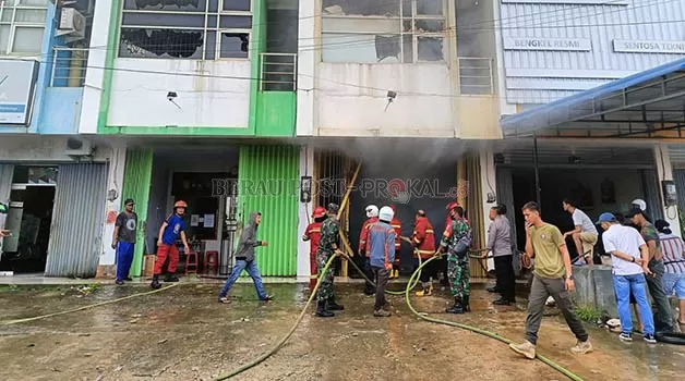 BERJIBAKU: Personel BPBD Berau, bersama TNI/Polri dan juga masyarakat, berjibaku membuka pintu terali ruko untuk memadamkan api di dalam bangunan tersebut.