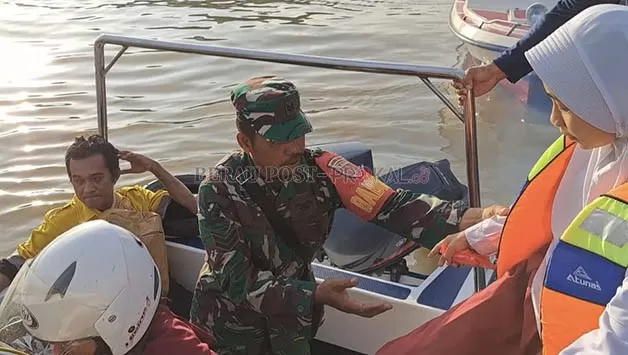 MENYEBERANG: Seorang Babinsa Koramil 0902-04 Tanjung Redeb, saat membantu para pelajar naik dan turun dari speedboat di Dermaga Sanggam.